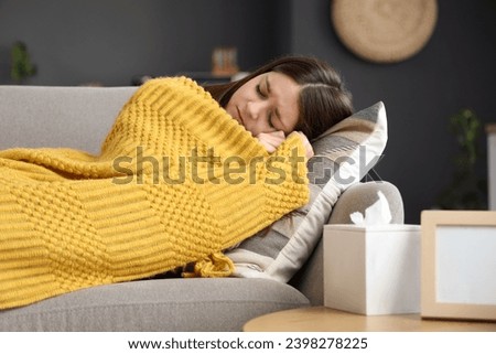 Sick little girl with plaid lying on sofa at home
