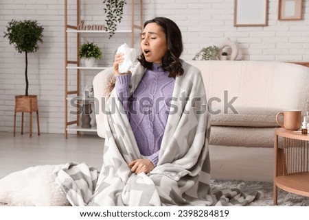 Sick young woman with plaid and tissue at home
