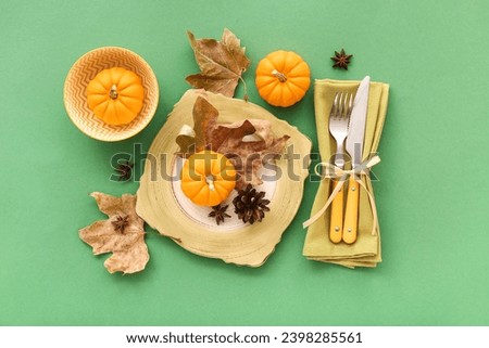 Autumn table setting with pumpkins, star anise and dried leaves on green background
