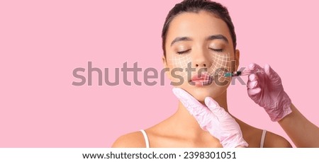 Young woman receiving filler injection in face against pink background with space for text. Skin care concept Royalty-Free Stock Photo #2398301051