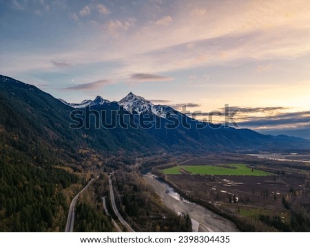 Scenic Road in Valley by the River, surrounded by Mountains. Sunset, Fall Season. Aerial Landscape. Fraser Valley, British Columbia Canada. Royalty-Free Stock Photo #2398304435