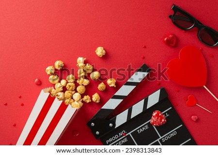 Cinematic Love Symphony: Overhead composition featuring slate, 3D glasses, spilled popcorn, candies, and heart-themed decor on vibrant red canvas— charming setup for Saint Valentine's Day movie debut Royalty-Free Stock Photo #2398313843