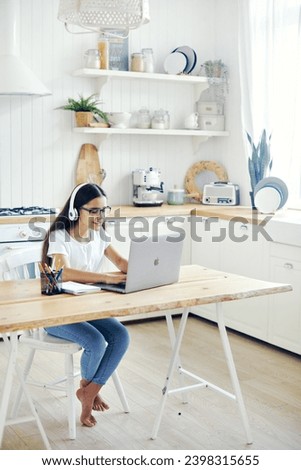 Pre-teen 12s girl in headphones and eyeglasses sit at table e-learns, listen online course, audio lesson, get new knowledge, skills using internet and modern tech. Development, education, eye-sight Royalty-Free Stock Photo #2398315655