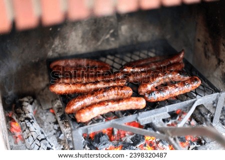 Photo view of pork sausages food that are being barbecued on a BBQ inside a fire place chimney, they looks juicy yummy tasty delicious, congratsto the chef