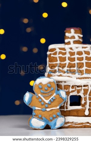 Christmas gingerbread in the shape of man is decorated with colorful sugar icing and a cookie house.