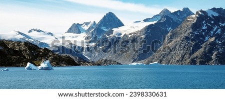 Europe; Greenland, East coast. Skoldungen fjord inhospitable, made up of steep mountains and bluish-colored icebergs that drift in deep fjords . Royalty-Free Stock Photo #2398330631