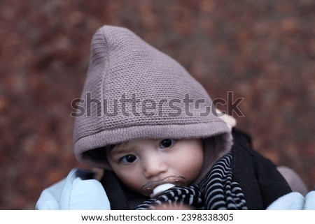 exterior top view photo of a eurasian handsome good looking cute adorable baby toddler during winter autumn with a dummy or teats in the mouth