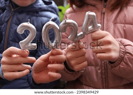 children's hands holding candles with numbers 2024. happy new year. Horizontal. faceless