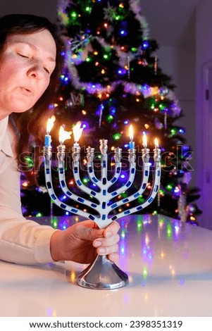 Judaic blowing on burning candles of Hanukkah menorah.