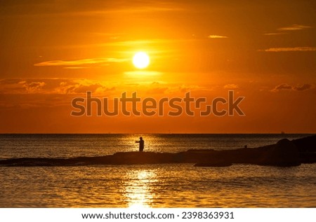 A man fishing at Lan Hin Khao, Mae Ramphueng Beach in Rayong Province of Thailand.Silhouette picture style.