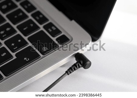 Black mini jack connector plugged into the modern ultrabook laptop. Analog audio connecton of modern device. Royalty-Free Stock Photo #2398386445