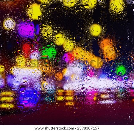City view through a window on a rainy night,Rain drops on window with road light bokeh, City life in night in rainy season abstract background. Focus on drops on glass