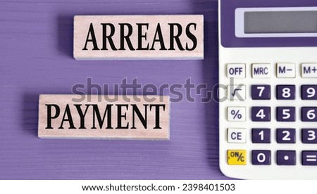ARREARS PAYMENT - words on wooden blocks with a calculator in the background. Business concept