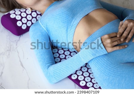 Crop photo of adult lady in blue sportswear lying body self health massage back neck acupressure mat. Woman doing on orthopedic acupressure therapy. Home healthcare medical concept. Copy ad text space