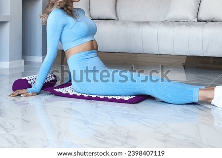 Lady doing body massage, self health massage at room, buttocks acupressure mat therapy. Cropped photo of woman sits on orthopedic acupressure mat. Home healthcare medical concept. Copy ad text space