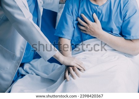 Side view of diverse doctors examining Asian female patient in bed in ward at hospital.