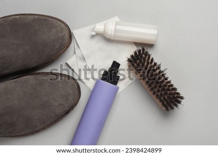 Suede chelsea boots with Shoe care products and accessories on gray background. Flat lay Royalty-Free Stock Photo #2398424899