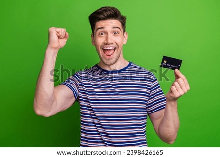 Photo of overjoyed cheerful person raise fist arm hold demonstrate debit card isolated on green color background