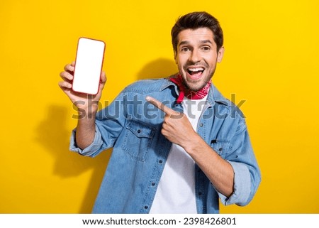 Photo portrait of nice young man point hold telephone white screen dressed stylish denim garment isolated on yellow color background
