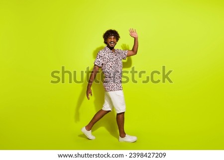 Full body photo of handsome young man walking wave hand hello wear trendy pink leopard print clothes isolated on yellow color background