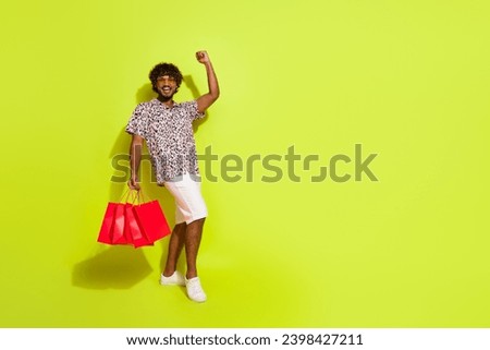 Full body photo of handsome young man shopping bags raise fist wear trendy pink leopard print clothes isolated on yellow color background