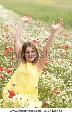 Top view of a girl sitting among a field of wild flowers, among poppies, cornflowers, daisies,The young woman feels happy and enjoys freedom in the middle of a poppy field, High quality photo