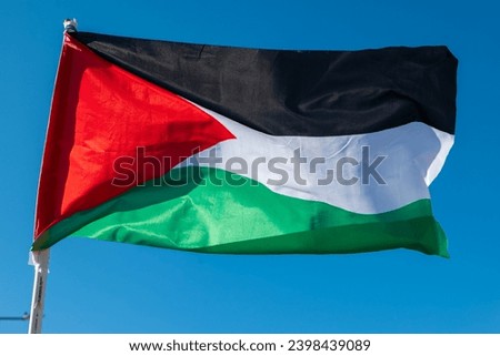 Palestine national flag waving in the air. Blue sky background