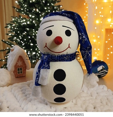 Christmas snowman against the background of burning lights of a festive garland and a New Year tree. decorating your home or office for a celebration. cheerful, festive mood