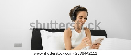 Portrait of young woman going to bed, wearing headphones and using smartphone, listening podcast or clam, relaxing music in earphones.