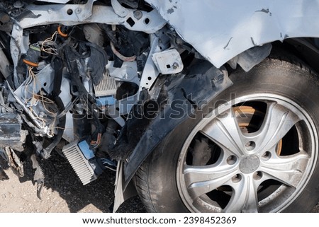car after an accident, severed wires dangle from the front of damaged vehicle, illustrating the aftermath of the collision. Royalty-Free Stock Photo #2398452369