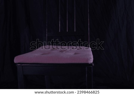 Black Chair in Front of Black Background with Pink Cushion
