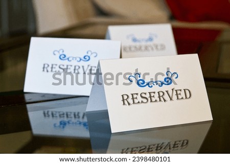 Reserved Signs with Ornate Blue Design on Reflective Glass Surface Close-Up