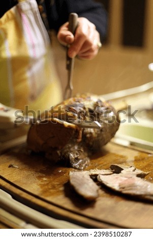Interior photo of a cuisine chef of cook who is cutting a delicious tasty juicy roast beef just baked from the oven at home or restaurant for a meal of diner or lunch for a familly together cathering