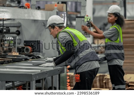 Skilled technician ensures machinery stays in optimal condition. Regular inspections, tests, repairs, upholding standards. Identifying malfunctions, errors for smooth operations in cardboard factory. Royalty-Free Stock Photo #2398536189