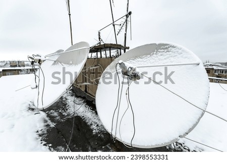 Telecommunications and satellite television. Communication problem due to bad weather. Satellite dishes covered with snow. Royalty-Free Stock Photo #2398553331