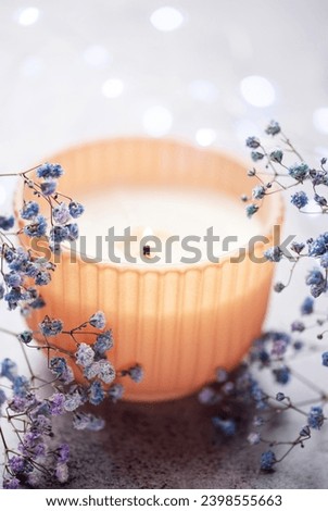 Candle and a branch of blue gypsophila flowers. 