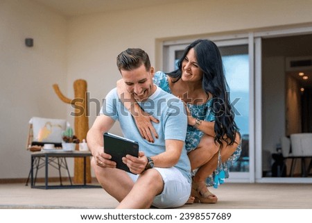 Woman embracing her boyfriend while using tablet sitting in the patio of a new house