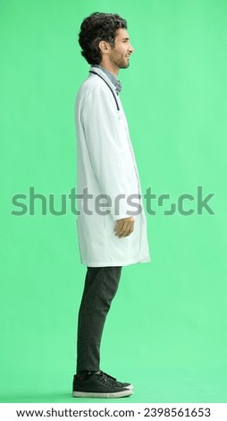 male doctor in a white coat on a green background in profile