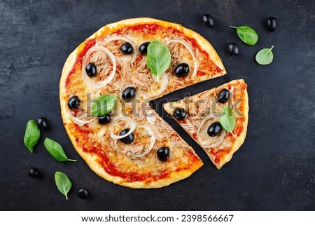Traditional Italian pizza al tonno with tuna, onion and olives served as top view on an old rustic board with text free space 