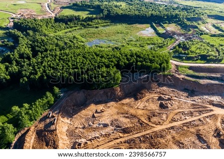 Aerial view of an old overgrown quarry in the background and an active sand quarry