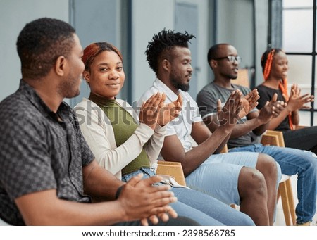 Group of men and women sit in a row and applaud a man who puts forward an idea or says something. Royalty-Free Stock Photo #2398568785