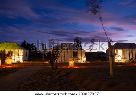 Luxury camp in the Sahara desert, with lights and the typical Haimas. Photo taken at dusk.