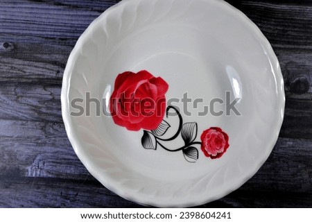 empty food plate used for serving food, with a picture of a red rose flower on the plate, utensils, kitchenware, and food concept, plastic deep plates, selective focus