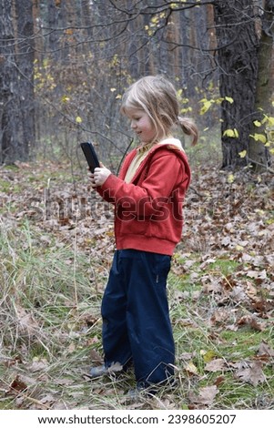 A girl in the forest takes pictures with a smartphone.
