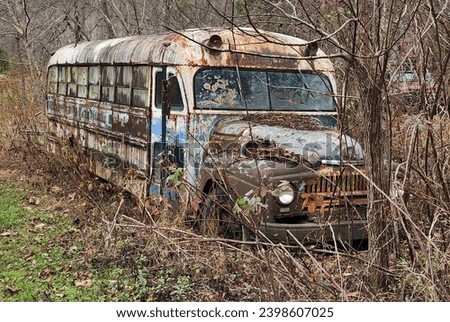This is a picture of an old and dilapidated bus that has been abandoned in the countryside. The bus is rusted and peeling, with broken windows and tires. 