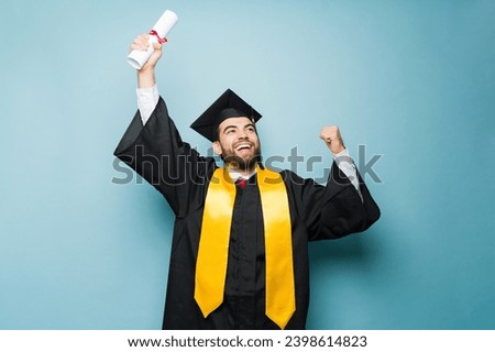 Happy excited latin man screaming and celebrating receiving his college diploma while wearing a graduation gown and cap Royalty-Free Stock Photo #2398614823