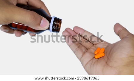 man hand holding orange pills and jar in his hands. Concept of healthcare and medicine, patient take daily dose of prescribed medicament, feel sick, antibiotics, painkillers or antidepressants. Royalty-Free Stock Photo #2398619065