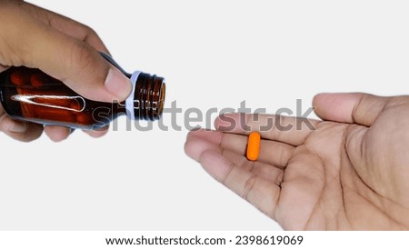 man hand holding orange pills and jar in his hands. Concept of healthcare and medicine, patient take daily dose of prescribed medicament, feel sick, antibiotics, painkillers or antidepressants. Royalty-Free Stock Photo #2398619069