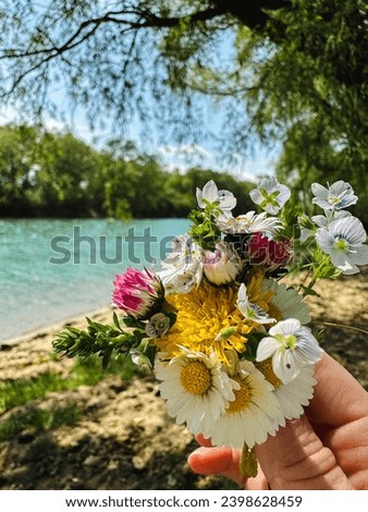 a small bouquet of wildflowers in the hands against the background of the river