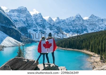 Tourists draped in Canadian flag looking beautiful scenery of Moraine lake. Banff National Park. Canadian Rockies. Alberta, Canada.
 Royalty-Free Stock Photo #2398636349